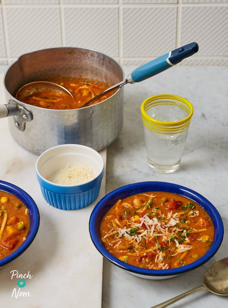 Pinch of Nom's Minestrone Soup is served in two large bowls, topped with shavings of Parmesan cheese and a sprinkling of pepper.