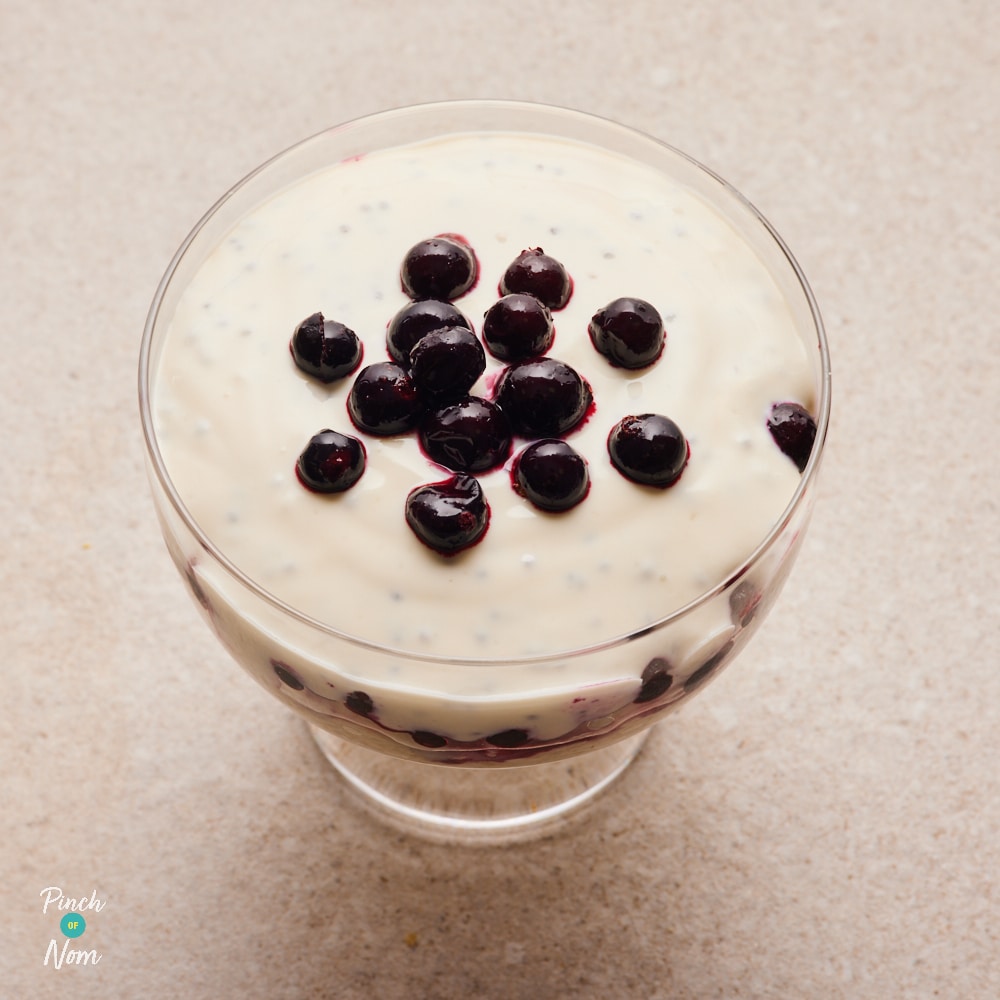 Apple and Blackcurrant Oats Mixture in a glass trifle bowl, topped with blackcurrants.