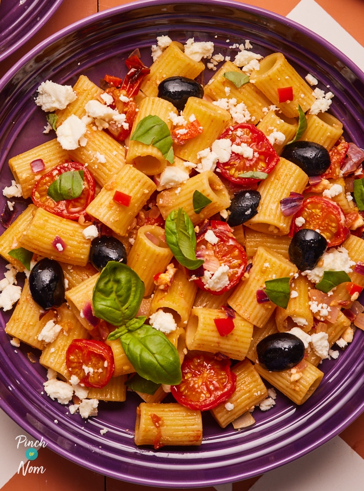 Garlic and chilli pasta, served in a bowl and topped with olives, feta, and basil.