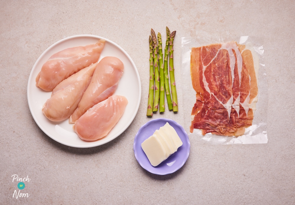 The raw ingredients for Pinch of Nom's slimming-friendly Mozzarella and Asparagus Stuffed Chicken are laid out on a kitchen counter, ready to begin cooking.
