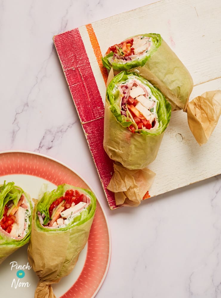 Pinch of Nom's Low Carb Chicken and Ham Wraps are served sliced in half on a serving board.