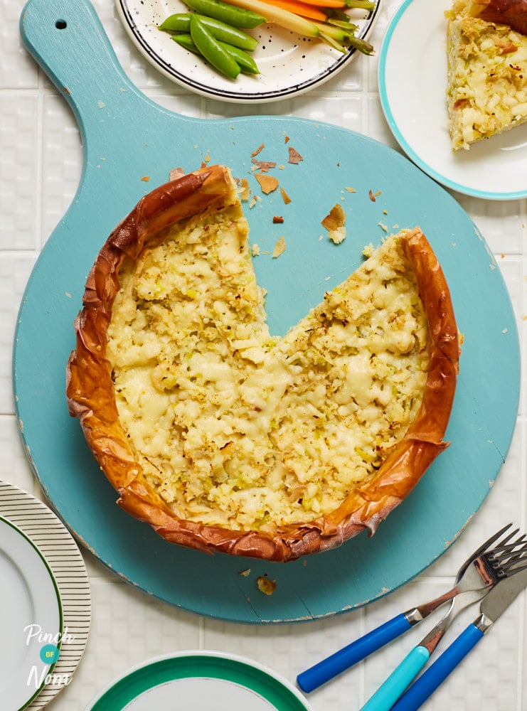 Pinch of Nom's slimming-friendly Homity Pie is served with one slice removed, revealing the cheesy middle and flaky pastry crumbs.