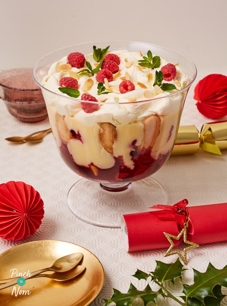 A dessert dish at the centre of a festive table is filled with Pinch of Nom's slimming-friendly Christmas Trifle; it's topped with berries, sprigs of mint and flaked almonds.