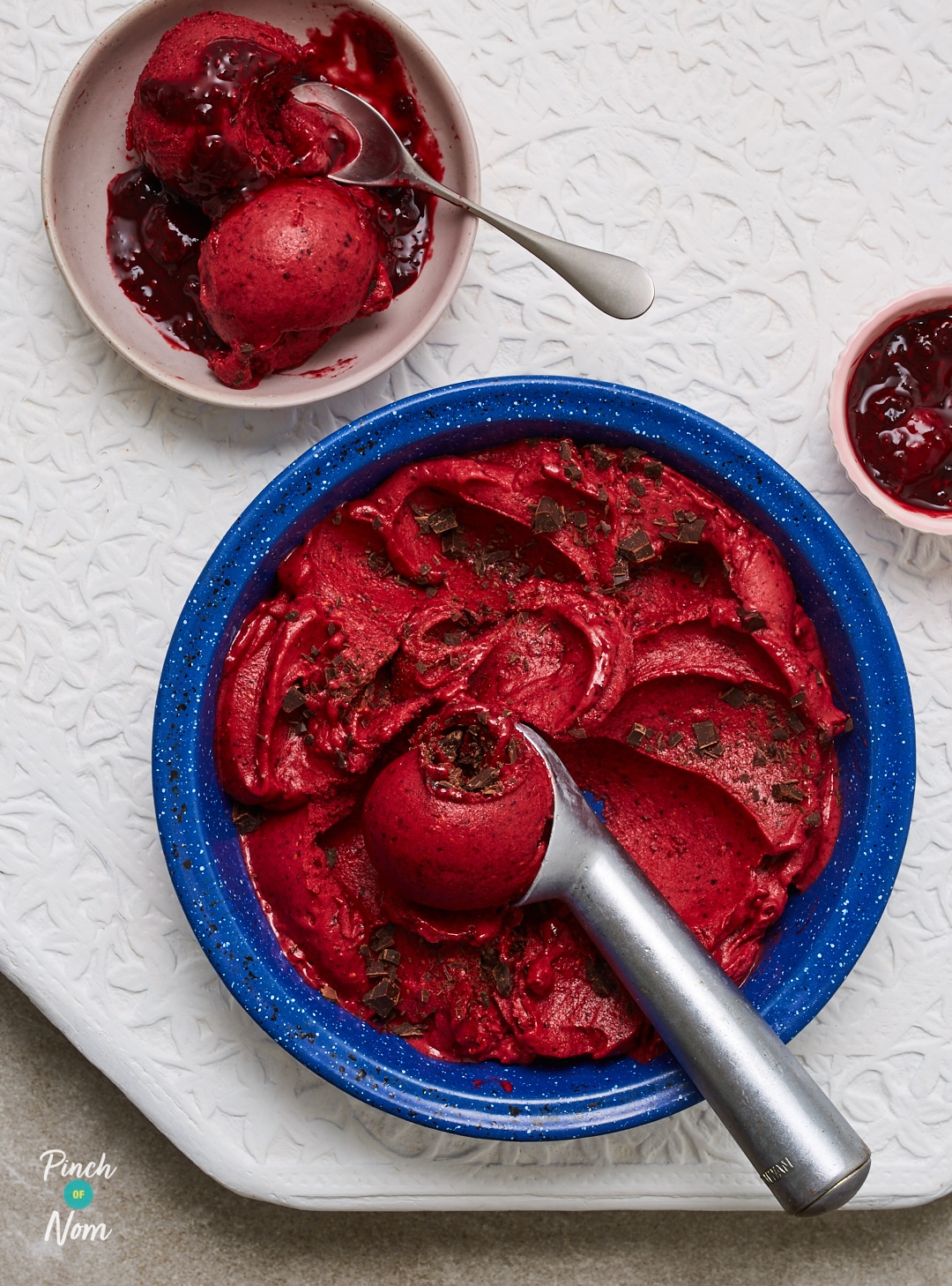 A spoon scoops Pinch of Nom's slimming-friendly Winter Berry Ice Cream into smaller bowls, ready to tuck in.