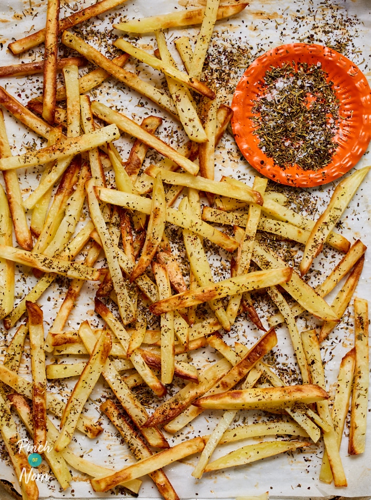 A tray of Pinch of Nom's Za'atar Fries is fresh from the oven looking golden and crunch, covered in a herby mixture.