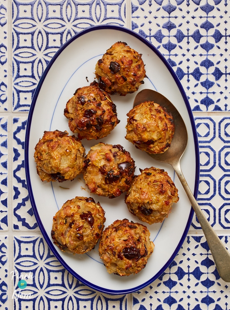 A large serving plate is filled with Pinch of Nom's slimming-friendly Cranberry and Orange Stuffing Balls at the centre of a blue and white mosaic-patterned countertop.