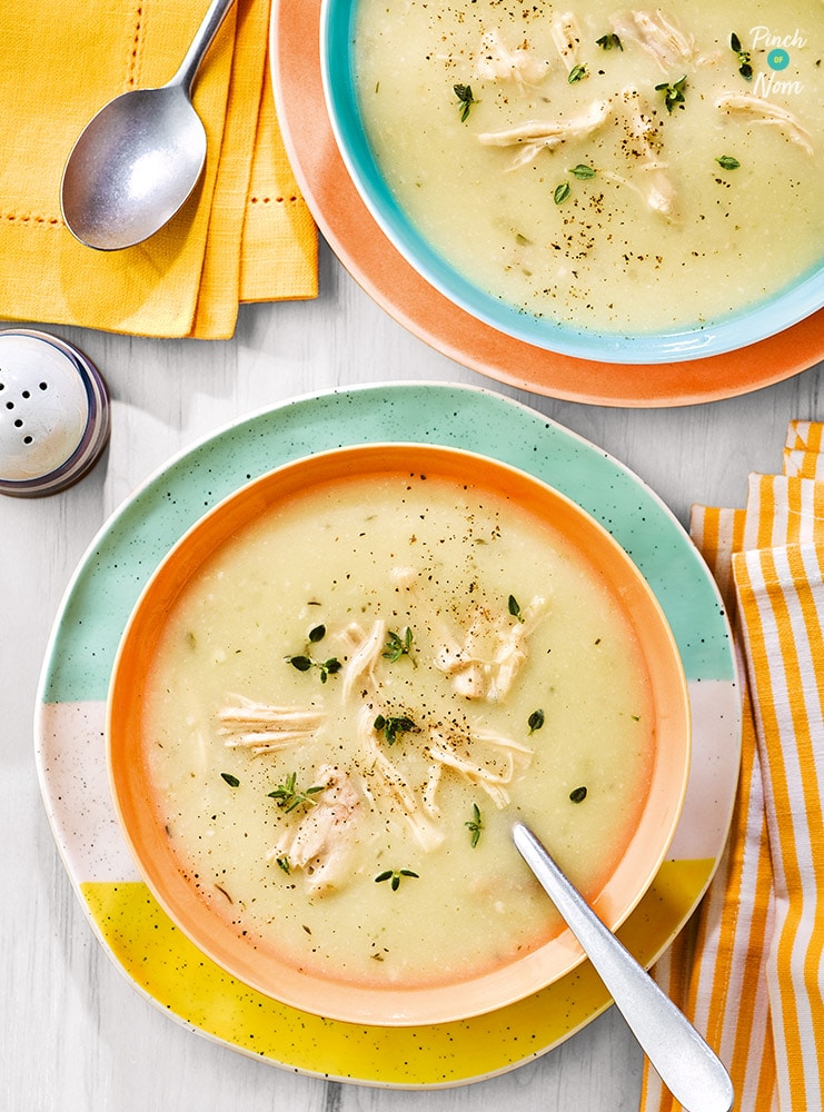 Two bowls are filled with Pinch of Nom's Creamy Chicken Soup from the Comfort Food cookbook. A spoon is waiting to tuck in, and each portion is topped with a sprinkling of basil and pepper.