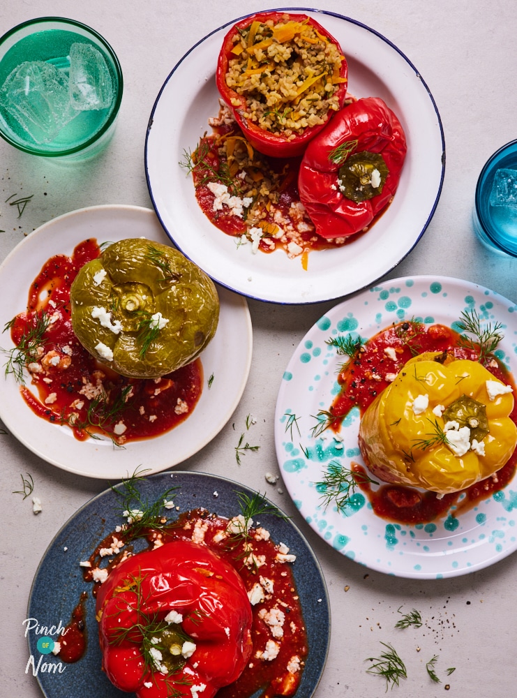 Four of Pinch of Nom's Mediterranean Style Stuffed Peppers are plated up with the tops cut off and the filling of feta cheese, beef, bulgur wheat and veggies bursting onto the plate.