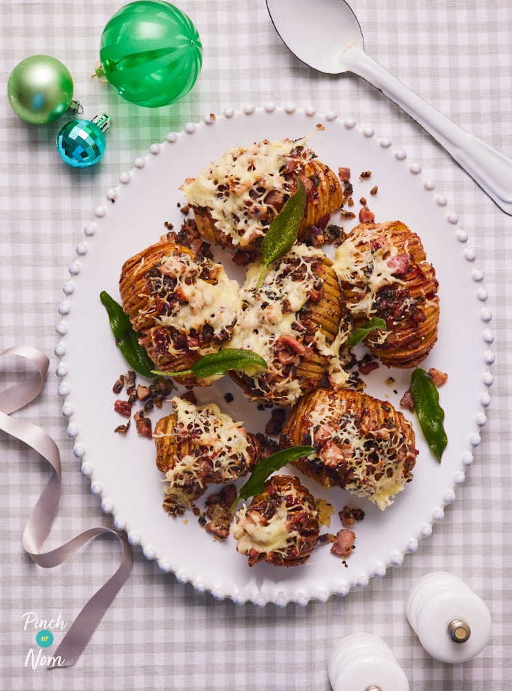 A plate is full with Pinch of Nom's slimming-friendly Christmas Hasselback Potatoes.