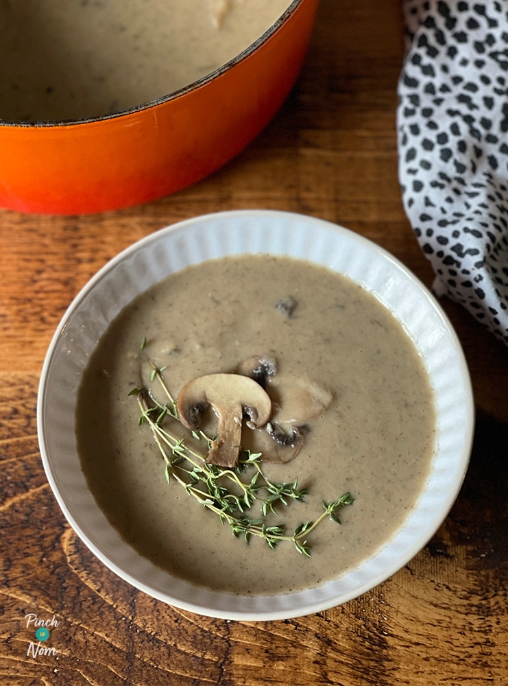 A bowl is filled with a portion of Pinch of Nom's Garlic Mushroom Soup from the Pinch of Nom: Enjoy cookbook. The top is garnished with chives and extra sliced mushrooms.