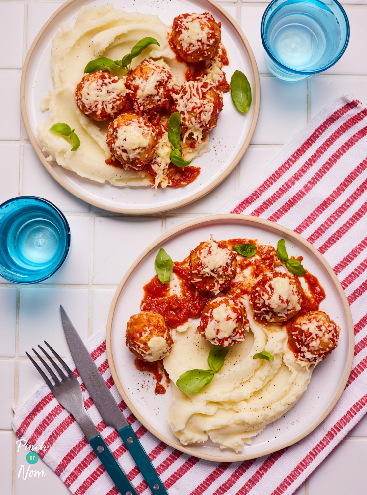 A table is set with two plates of Pinch of Nom's slimming-friendly Hunter's Chicken Meatballs recipe; both portions are served with a side of creamy mashed potatoes and topped with fresh basil leaves.