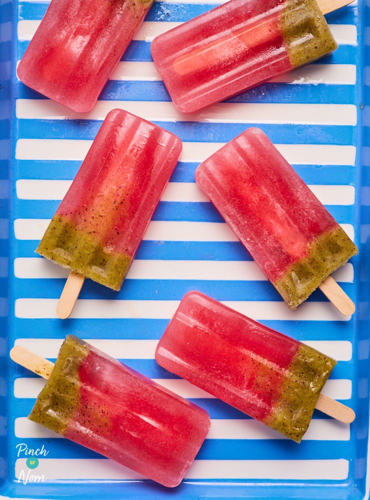 On a blue stripy background, 6 Strawberry and Kiwi Ice Lollies are laid out. They are juicy and red at the top, with a layer of green kiwi at the bottom.
