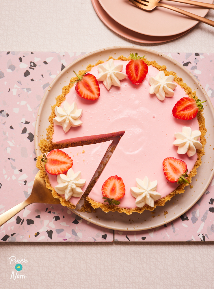 Pinch of Nom's slimming-friendly Strawberry Cream Pie is served on a bright pink chopping board.