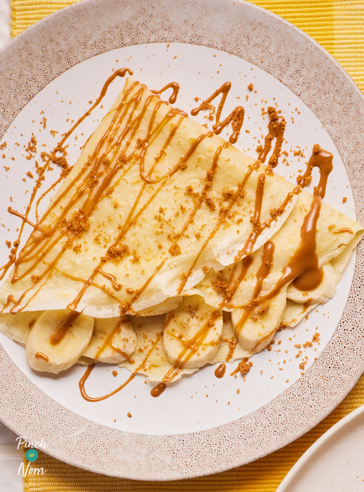 A close-up of Pinch of Nom's Banana and Biscoff Pancakes topped with crumbled Biscoff biscuits and a drizzle of smooth Biscoff spread.