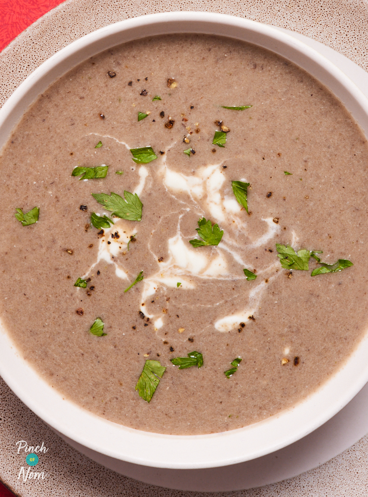 A close-up of Pinch of Nom's low-calorie Cream of Mushroom Soup. The soup is creamy and rich, served with a sprinkle of chopped parsley leaves.