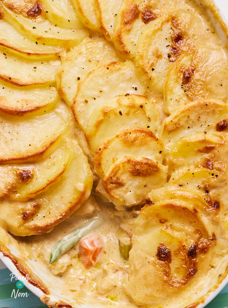 A close-up of Pinch of Nom's Creamy Vegetable Hotpot showshow crispy and golden the potato topping is, with the creamy vegetable filling peeking out underneath.