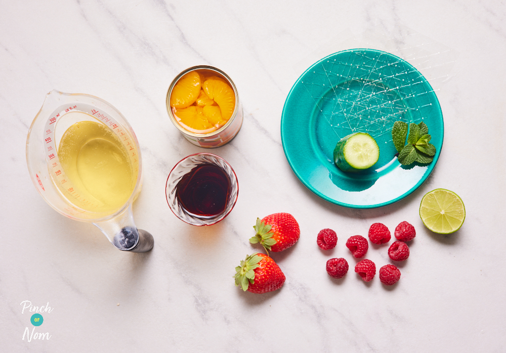 The ingredients for Pinch of Nom's Pimms Jelly are set out on a kitchen worktop. Each ingredient is portioned out in individual bowls andn on plates, waiting to begin cooking.