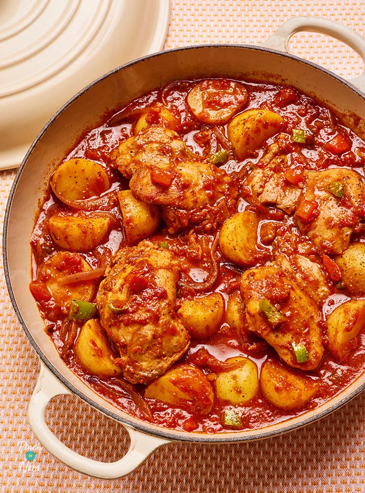 A large pan is filled with slimming-friendly Slow Cooker Cajun-Style Chicken Thighs from Pinch of Nom's All in One cookbook.