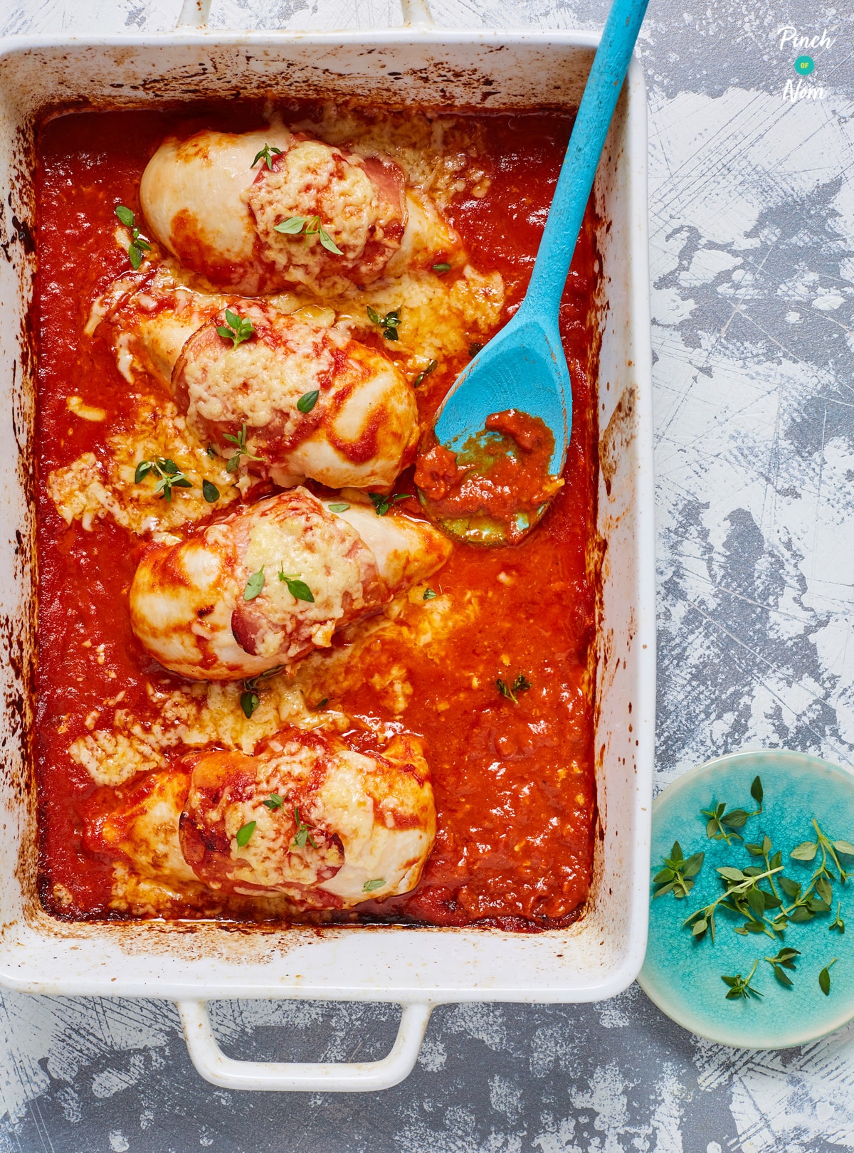A serving dish is filled with a few servings of Pinch of Nom's Slow Cooker Hunter's Chicken surrounded by a tomato sauce.