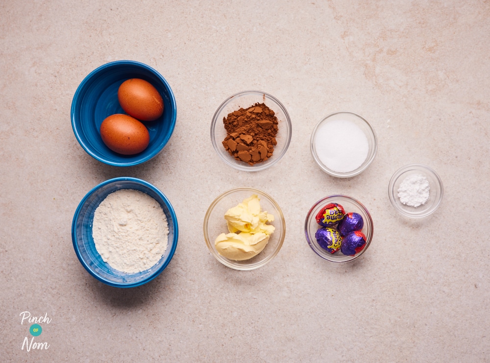 The raw ingredients for Pinch of Nom's Creme Egg Lava Cakes are laid out on a kitchen counter, ready to begin baking.