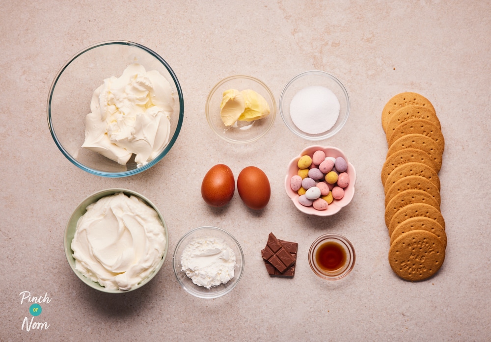 The raw ingredients for Pinch of Nom's Mini Egg Cheesecake are laid out on a kitchen counter, ready to begin baking.