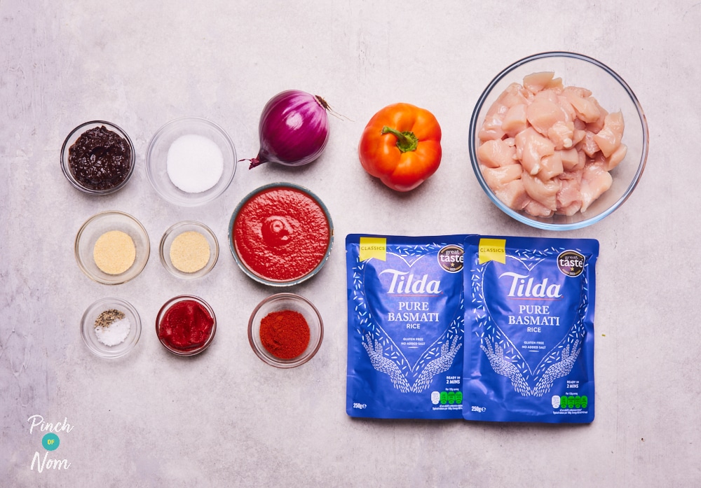 The raw ingredients for Pinch of Nom's Smoky Chicken and Rice Traybake are laid out on a kitchen counter, ready to begin cooking.