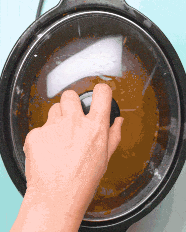 The lid is placed on top of a grimy slow cooker pot, filled with a fizzing combination of baking soda, white vinegar and warm water.