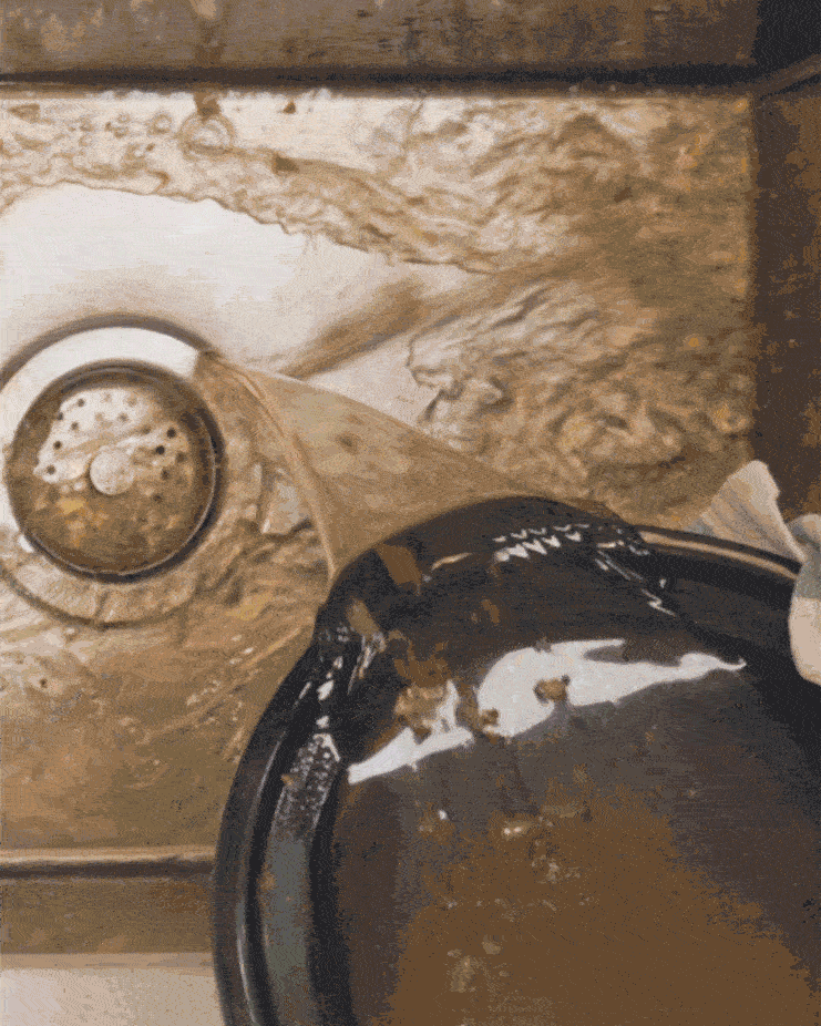 A slow cooker pot filled with dirty water is emptied into a sink.