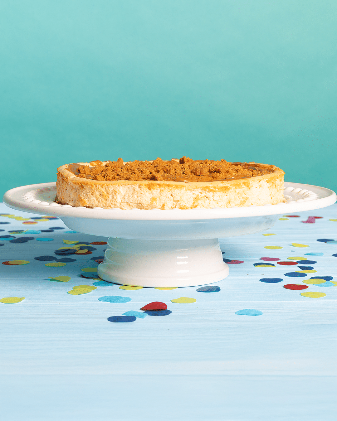 Pinch of Nom's Biscoff Cheesecake is served at the centre of a party table decorated with confetti.