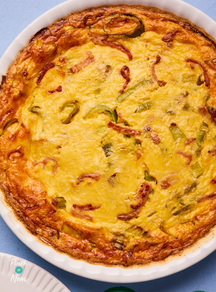 Pinch of Nom's slimming-friendly Carbonara Quiche is served freshly baked from the oven at the centre of a blue tabletop.