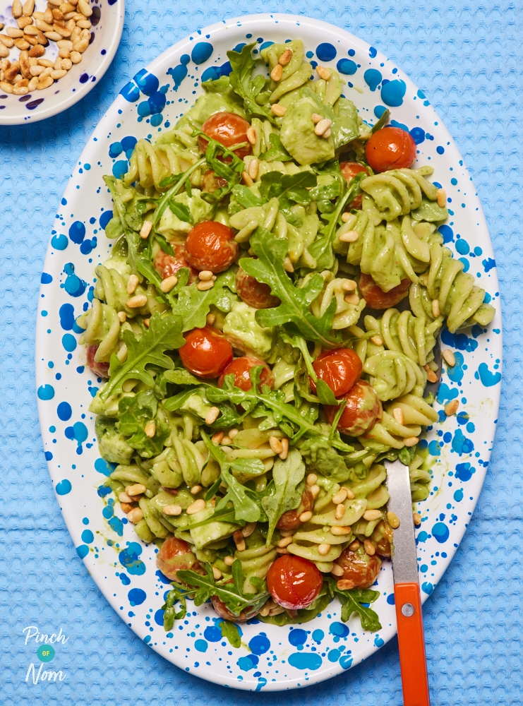 Pinch of Nom's slimming-friendly Pesto Pasta Salad is served at the centre of a table, with a large spoon waiting to dish out.