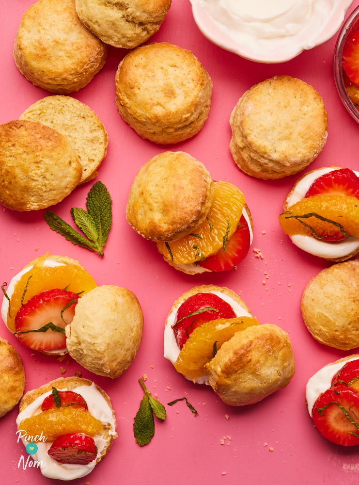 A pink tabletop is filled with a freshly-baked batch of fruity, cream-filled Pimm's Scones.